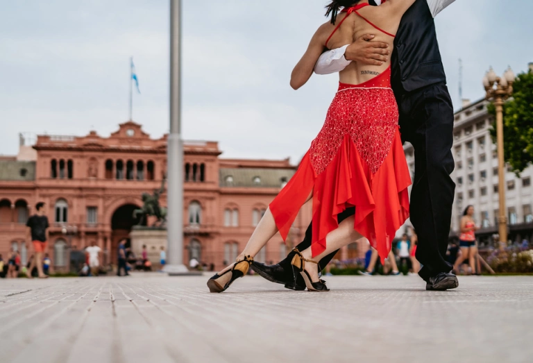Casal latino dançando tango na Plaza de Mayo, na cidade de Buenos Aires, Argentina, à luz do dia.